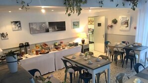 Comedor con mesas dispuestas para comidas, un bufé con diversas opciones de alimentos y una zona de cocina al fondo.