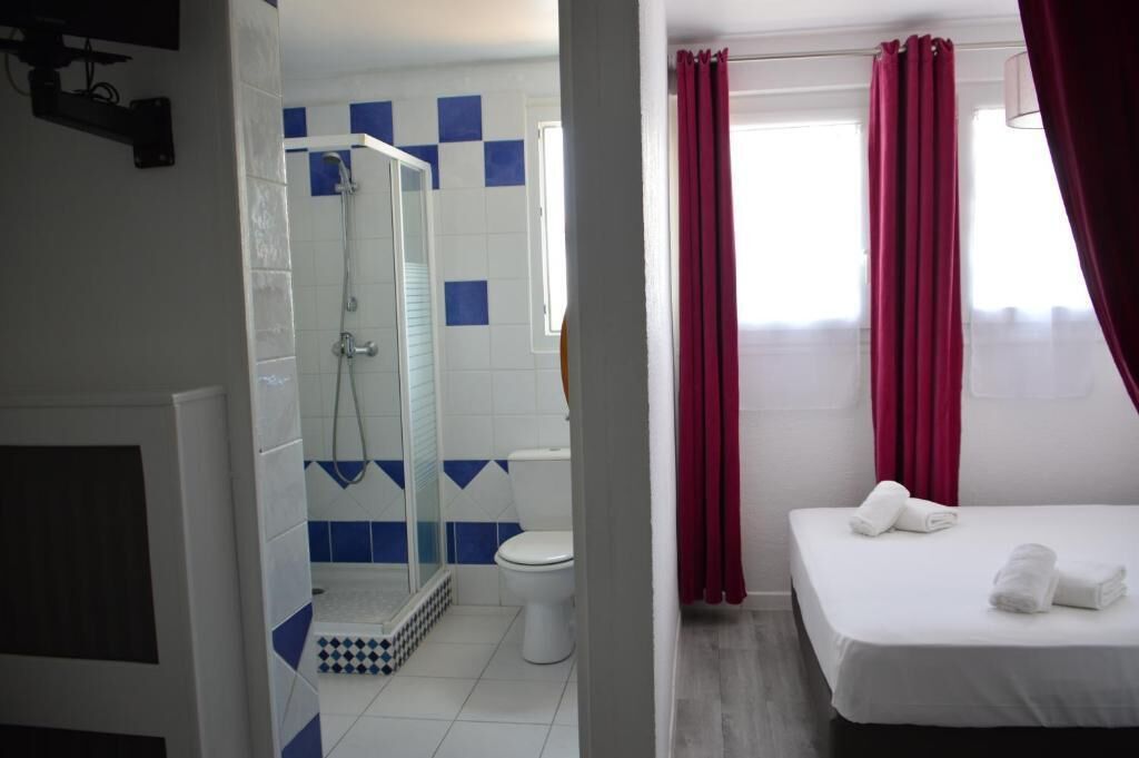 A hotel room with a shower, toilet, and bed.
