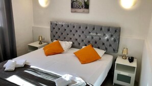 Una habitación de hotel con una cama grande, dos mesitas de noche, una lámpara de pared y un cuadro sobre la cama.