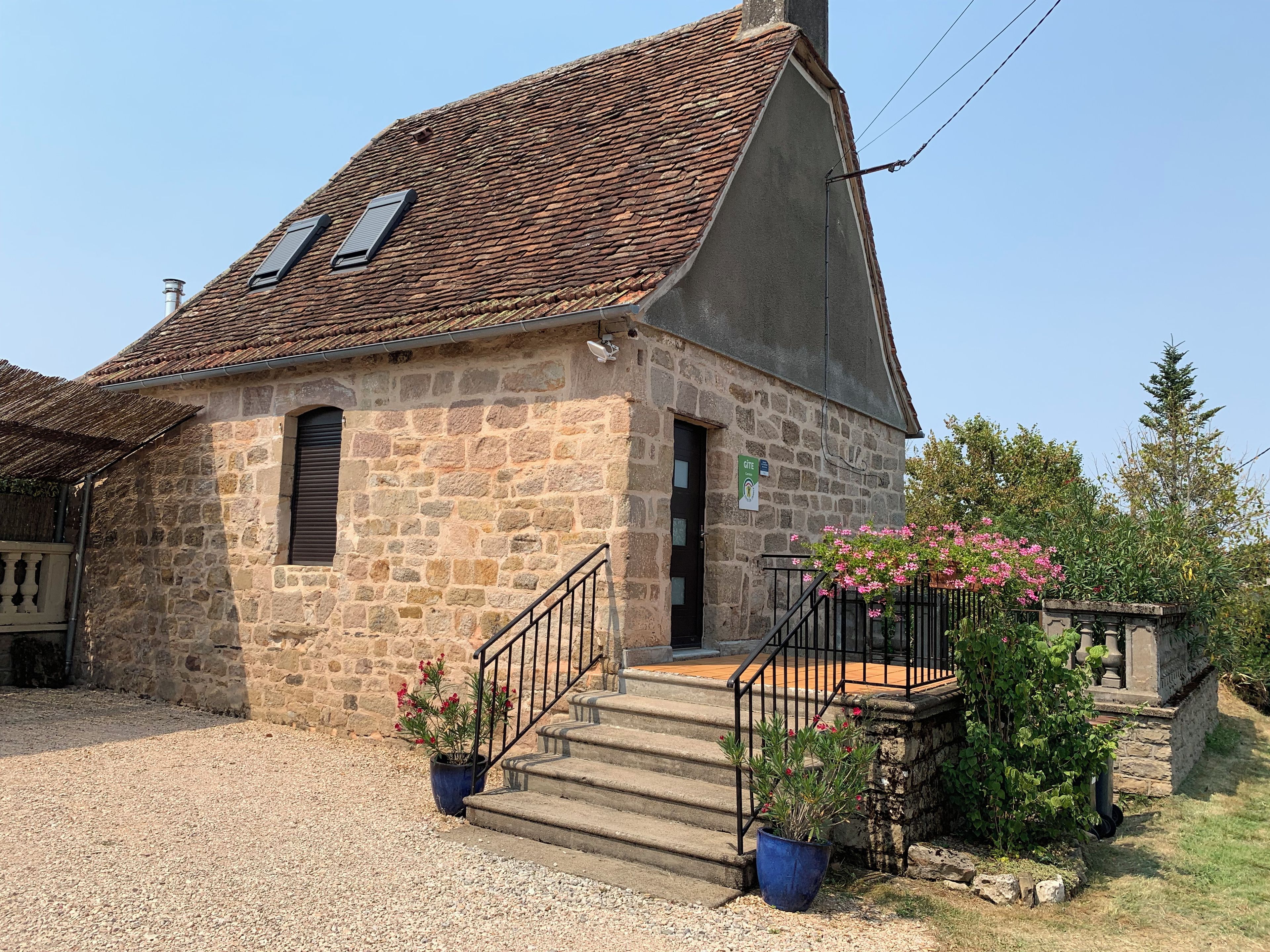 A stone building with a sloped roof, a small entrance, and a staircase leading to the entrance.