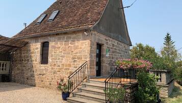A stone building with a sloped roof, a small entrance, and a staircase leading to the entrance.