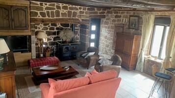 A cozy living room with a stone wall, a fireplace, a television, and comfortable seating.
