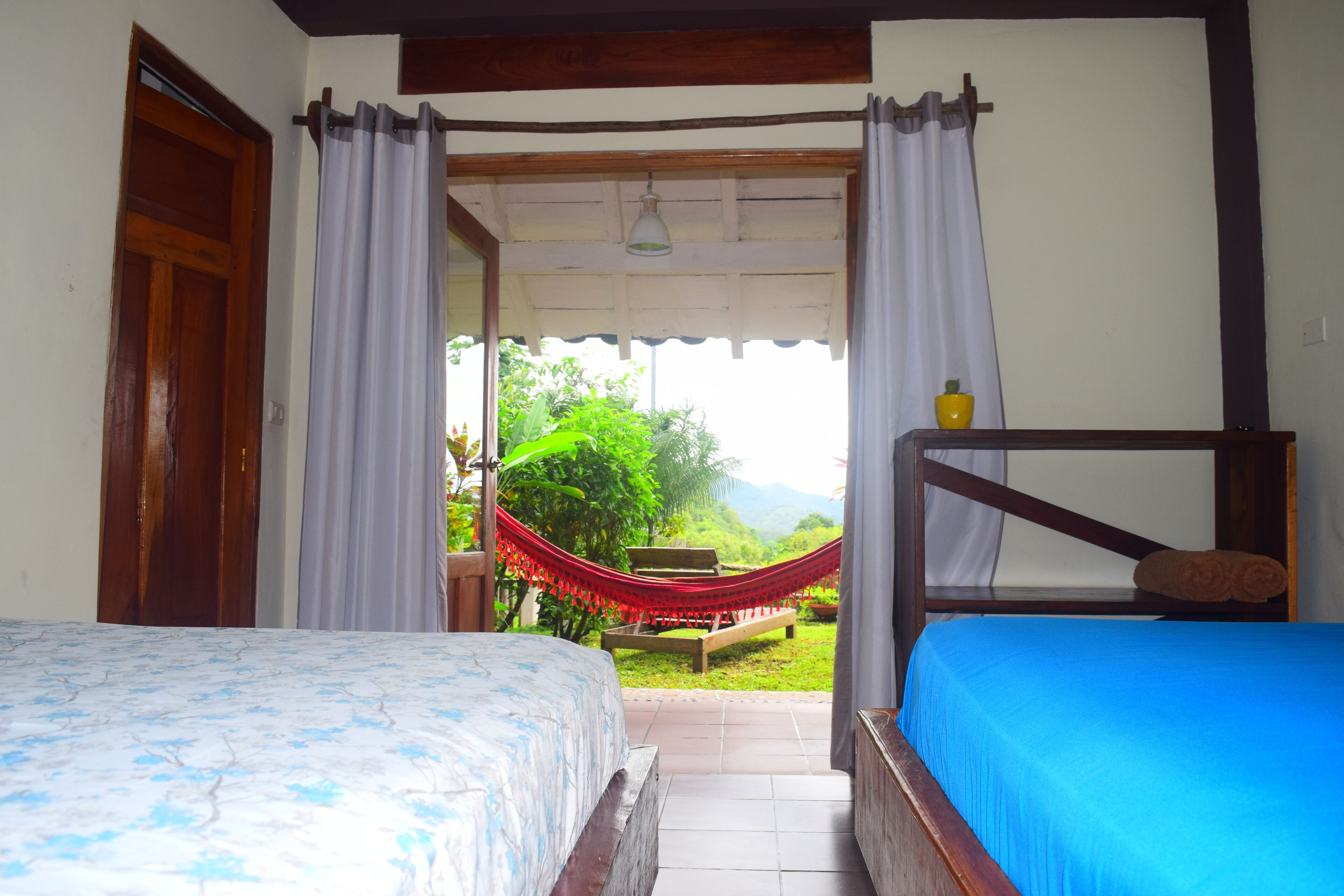 A bedroom with a bed, a wooden bench, and a hammock.