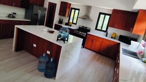 Una cocina moderna con una isla central, armarios de madera oscura y un ventilador de techo.