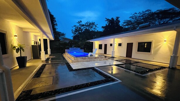 Una casa moderna con piscina, un patio luminoso y un sendero de piedra.