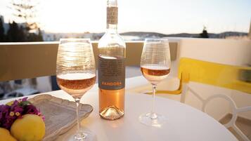 A table with two glasses of wine, a bottle of wine, and a tray with lemons and flowers.