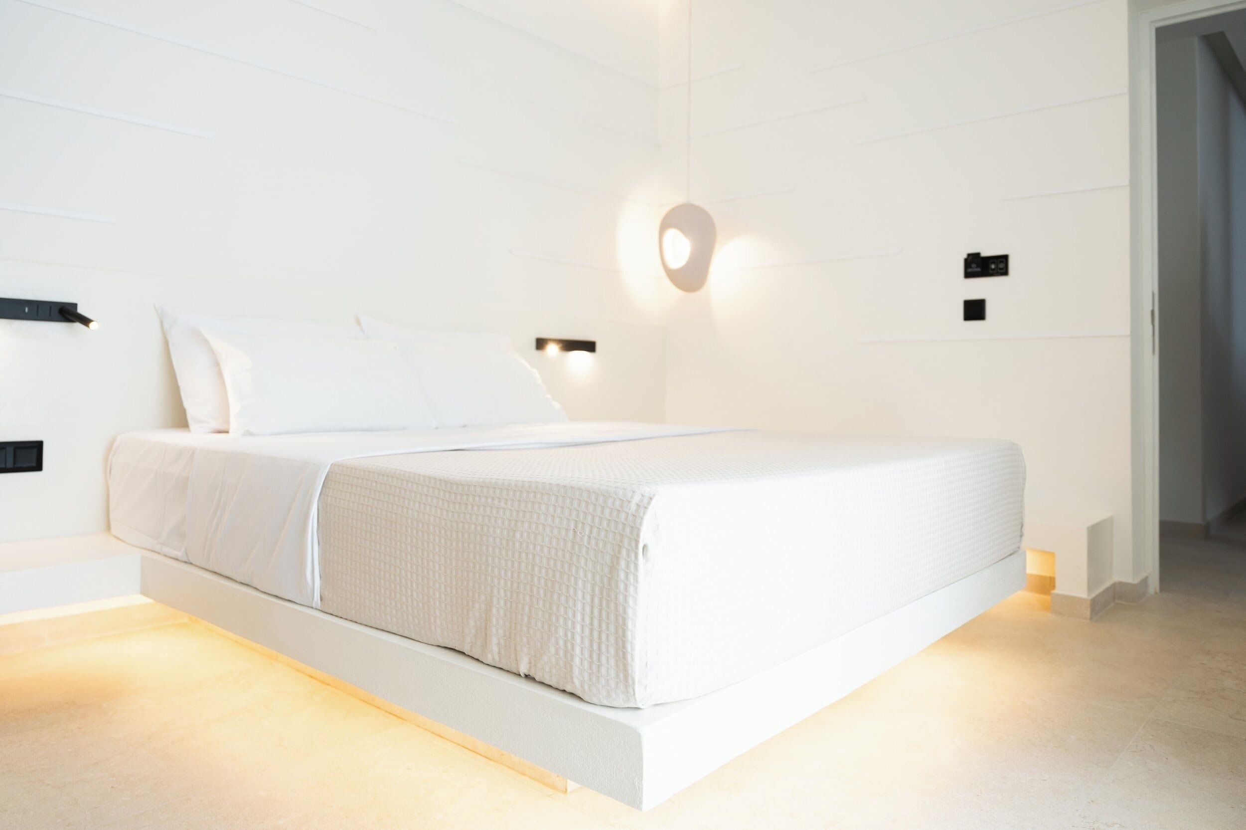 Un dormitorio moderno con una cama grande, paredes blancas y decoración minimalista.