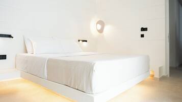 Un dormitorio moderno con una cama grande, paredes blancas y decoración minimalista.