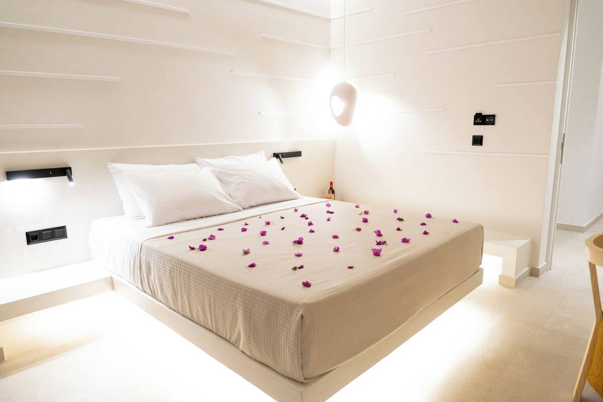 A modern bedroom with a large bed, white walls, and a minimalist design.