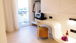 Een moderne hotelkamer met een wit, gebogen bureau, een houten stoel, een klein krukje, een wijnfles en een glas op het bureau.