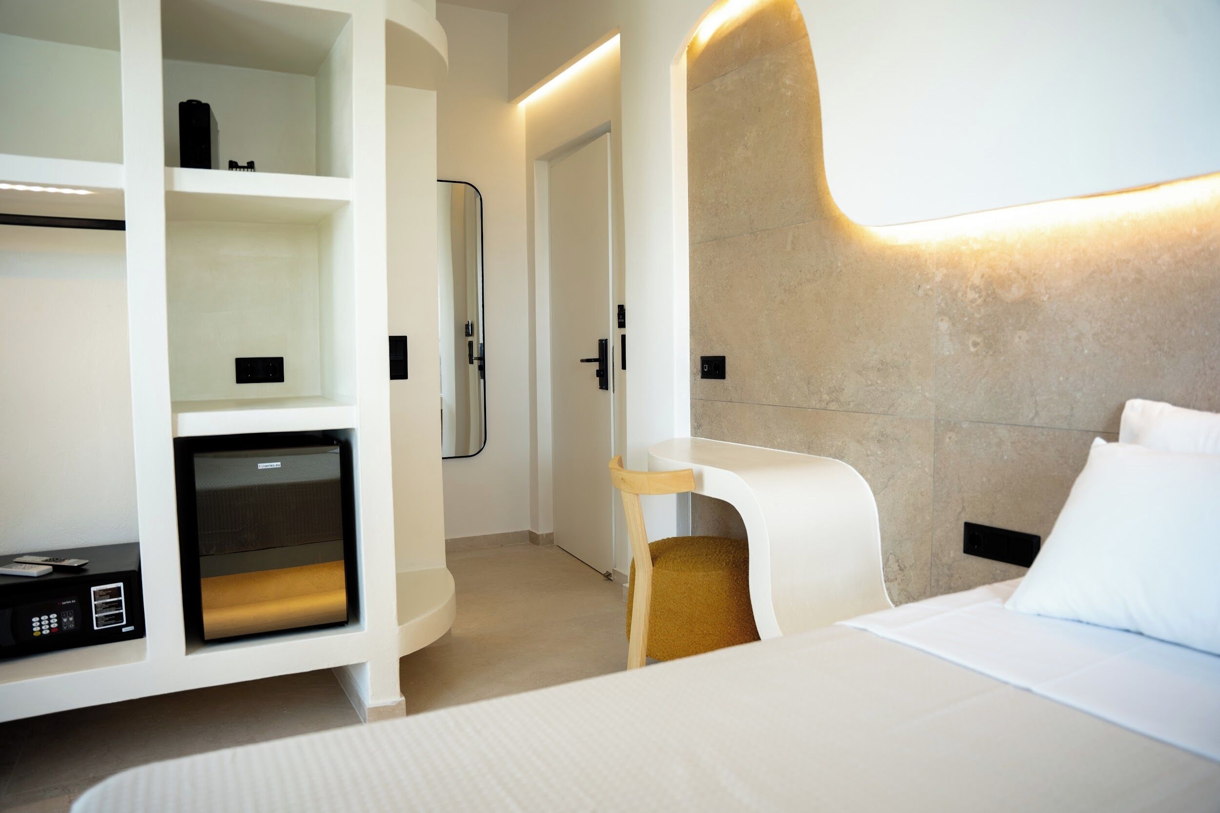 Une chambre d’hôtel moderne équipée d’un lit, d’un bureau intégré et d’un coin salon.