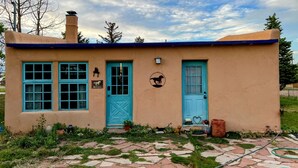 A small, single-story building with a blue door and windows, surrounded by a garden with a stone pathway. - Mountain getaway in the heart of La Veta! (La Veta)