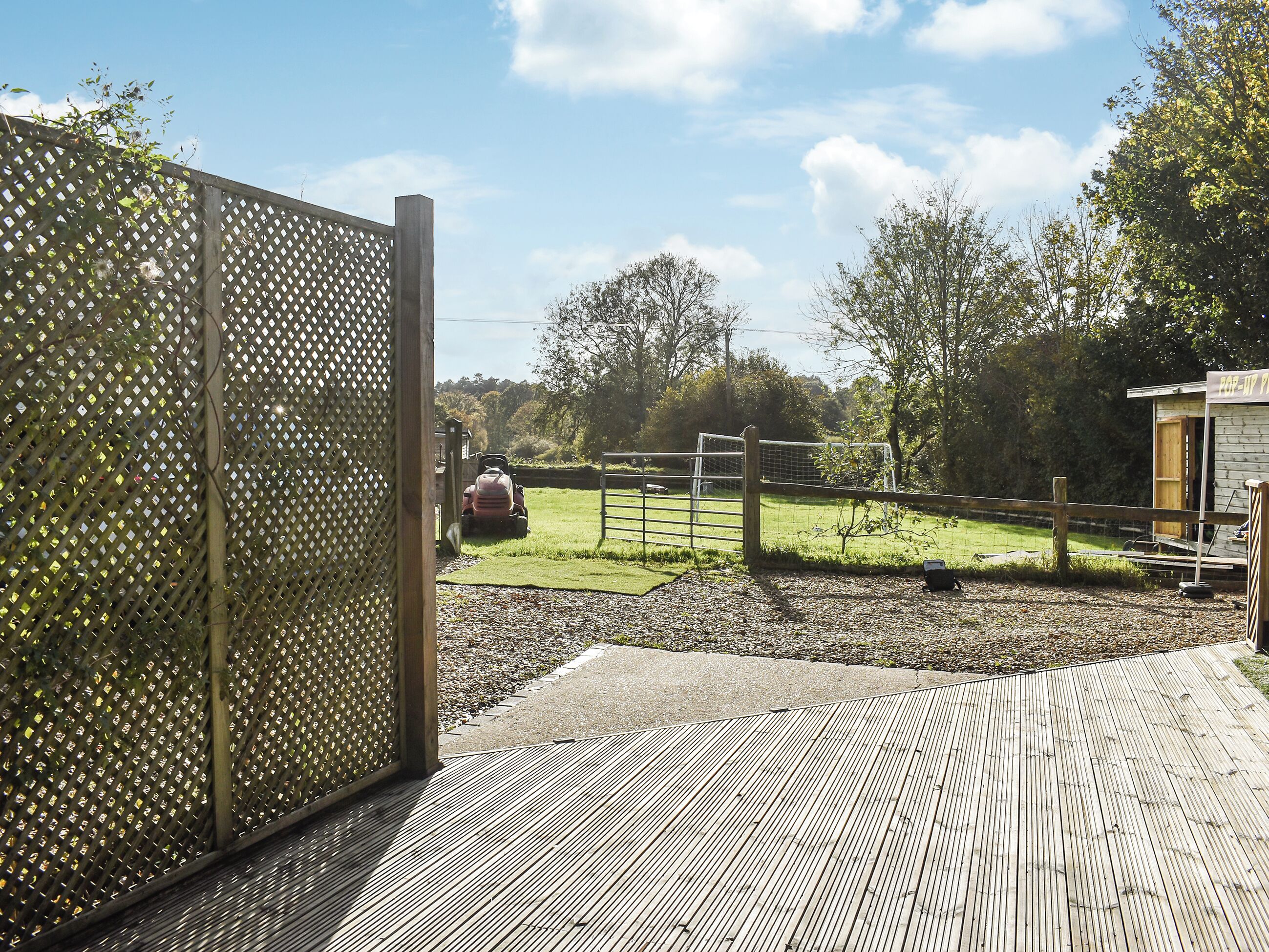 A wooden fence with a lattice design, a grassy field, and a building with a sign that reads "POP UP P."