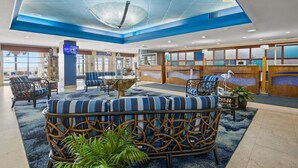 A lobby with a blue and white color scheme, featuring wicker furniture, a reception desk, and a large glass ceiling. - Spacious Oceanfront 2-bedroom Condo in Bay Watch in beautiful North Myrtle Beach (North Myrtle Beach)