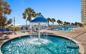 A pool area with a water fountain, lounge chairs, and palm trees. - Spacious Oceanfront 2-bedroom Condo in Bay Watch in beautiful North Myrtle Beach (North Myrtle Beach)