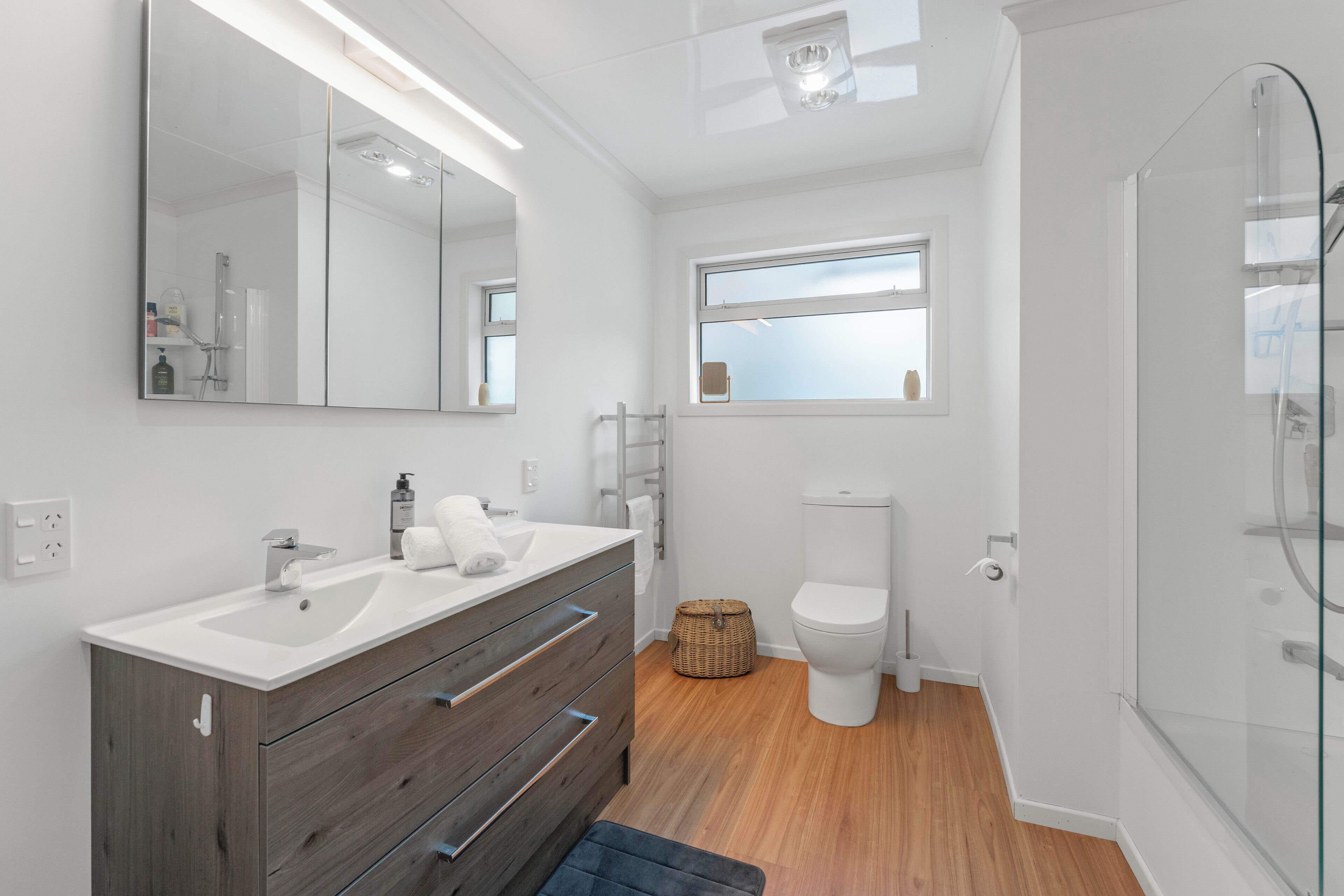 Un baño moderno con tocador doble, un espejo grande, inodoro y cabina de ducha con mampara de vidrio.