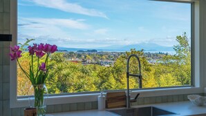 A kitchen with a large window, a vase with flowers, and a view of a city and mountains.