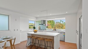 A modern kitchen with a large island, bar stools, and a view of the outdoors.