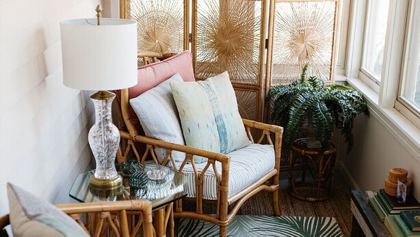 A cozy room with wicker furniture, a patterned rug, and a view through a window with a decorative screen.