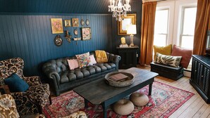 A cozy living room with a dark blue wall, a leather sofa, a coffee table, and a patterned rug.