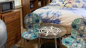 Une chambre à coucher comprenant un lit, un bureau, une chaise, une petite table et une bibliothèque.