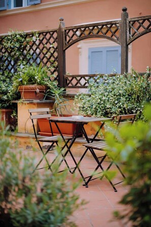 An outdoor patio with a wooden table and chairs, surrounded by potted plants and a lattice fence. - Navona Boutique Apartment with terrace (Rome)