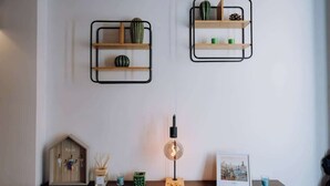A room with a wooden cabinet labeled 'Keys', a small table with a lamp, and two wall-mounted shelves with decorative items. - Navona Boutique Apartment with terrace (Rome)