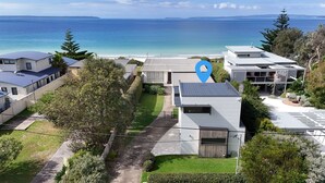 A residential area with modern houses, a clear view of the ocean, and a pathway leading to the beach. - Azure Studio - Ocean Glimpses - 3 Mins Walk to Beach (Callala Beach)