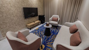 A modern living room with a flat-screen TV, two sofas, a coffee table, and a patterned rug. - XYZ Hotel - King Fahd Road (Riyadh)