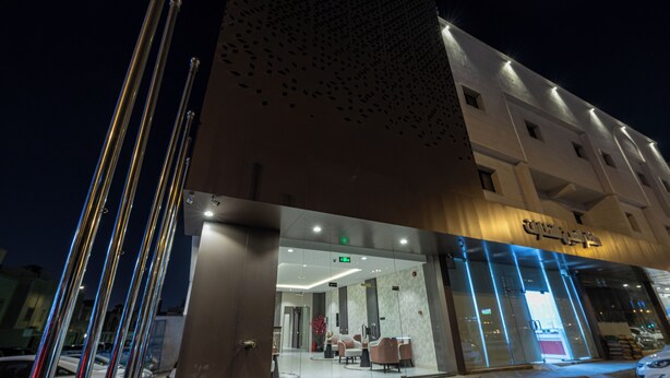 A modern hotel entrance with a glass facade, a reception area with seating, and a visible emergency exit sign. - XYZ Hotel - King Fahd Road (Riyadh)