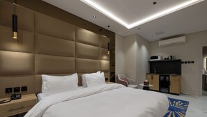 A modern hotel room with a large bed, bedside table with a phone, a TV, and a microwave on a cabinet. - XYZ Hotel - King Fahd Road (Riyadh)