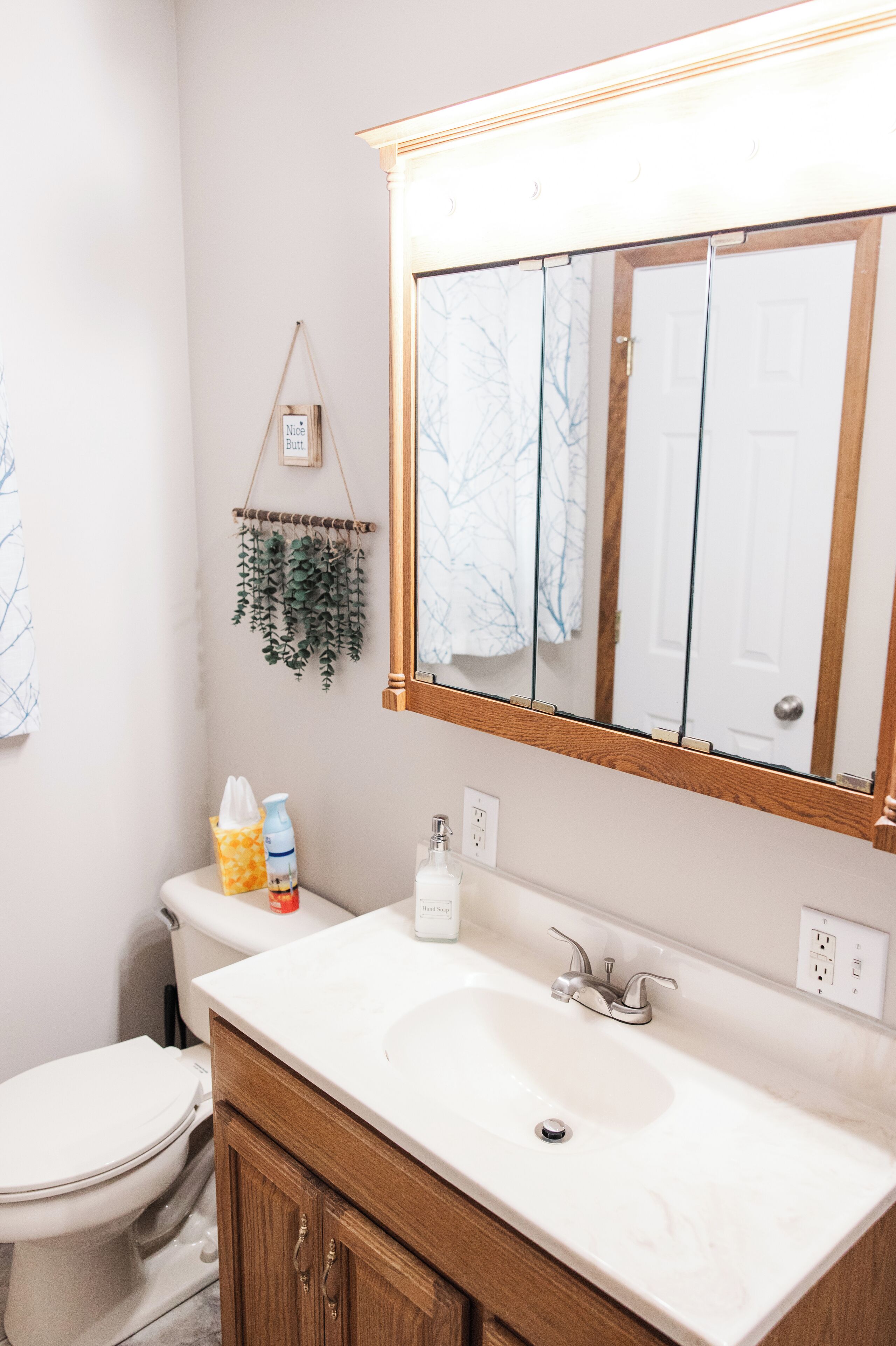 A bathroom with a white sink, wooden vanity, and a large mirror.
