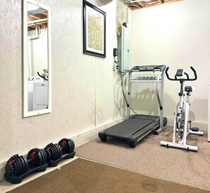 Un gimnasio en casa con cinta de correr, elíptica y mancuernas.