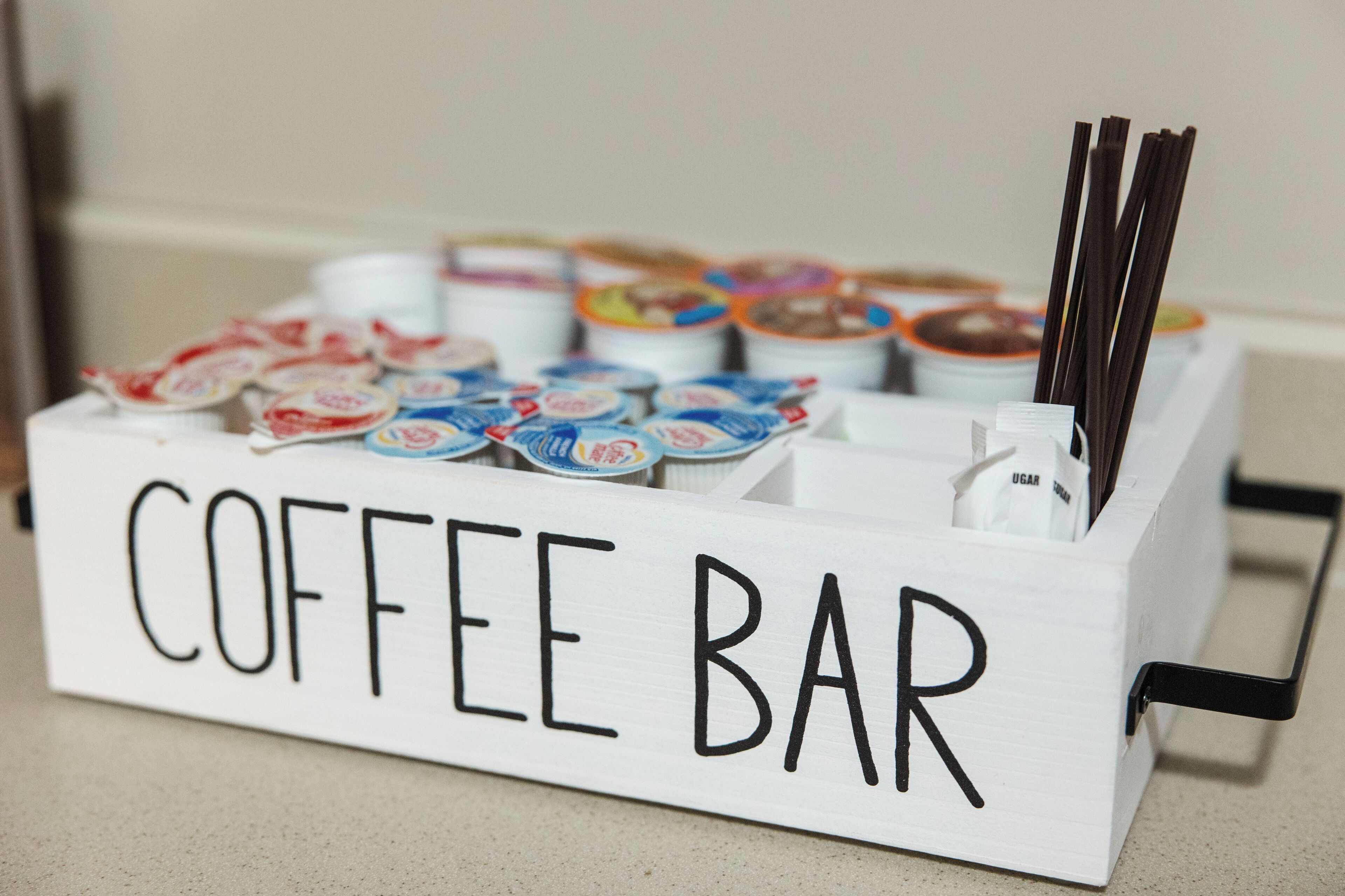 Una cafetería con recipientes etiquetados de café y sobres de azúcar.