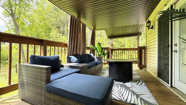 Eine überdachte Terrasse mit Korbmöbeln, einem Tisch und Blick ins Grüne.