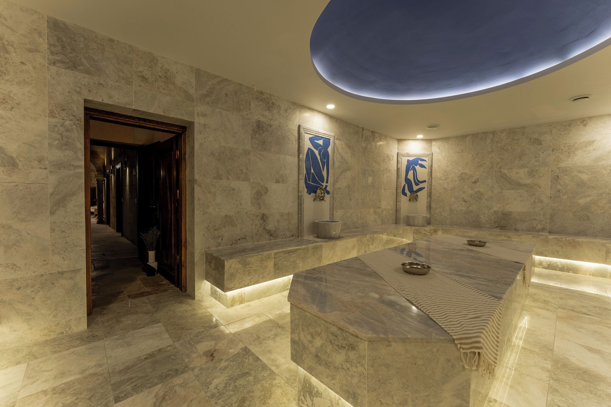 A modern lobby with marble flooring, a reception desk, and abstract wall art.