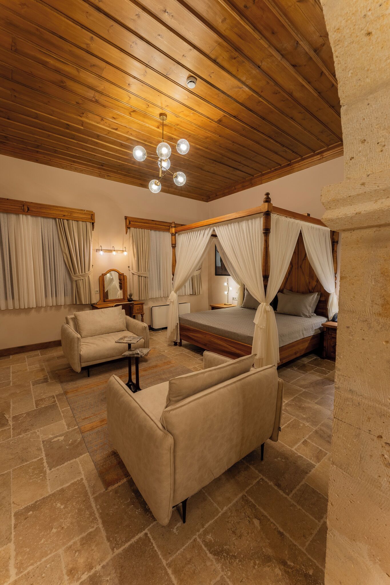 Une chambre à coucher avec un lit à baldaquin, un canapé, une table de chevet et une lampe.