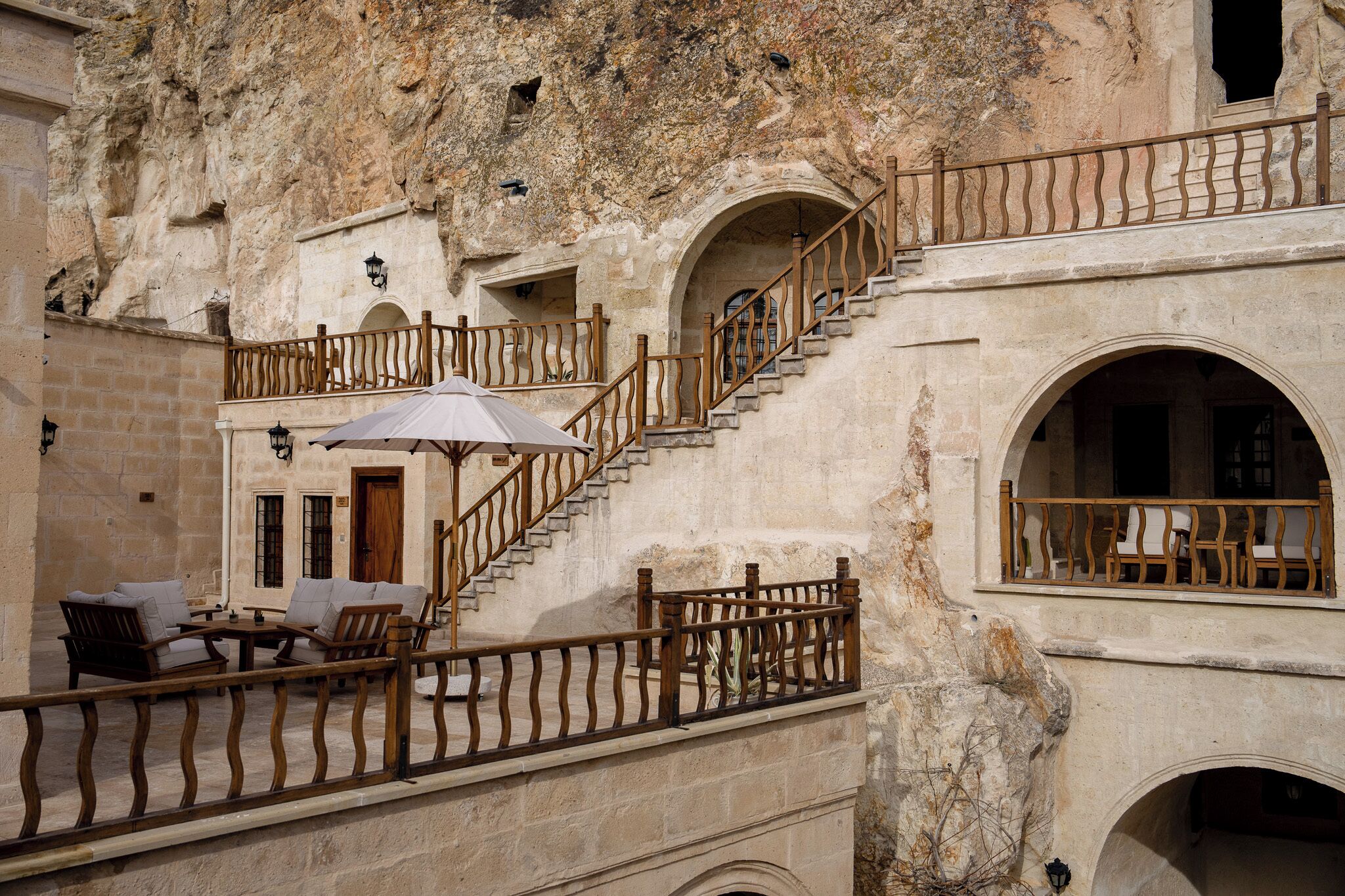 A stone building with a staircase, outdoor seating, and a balcony.