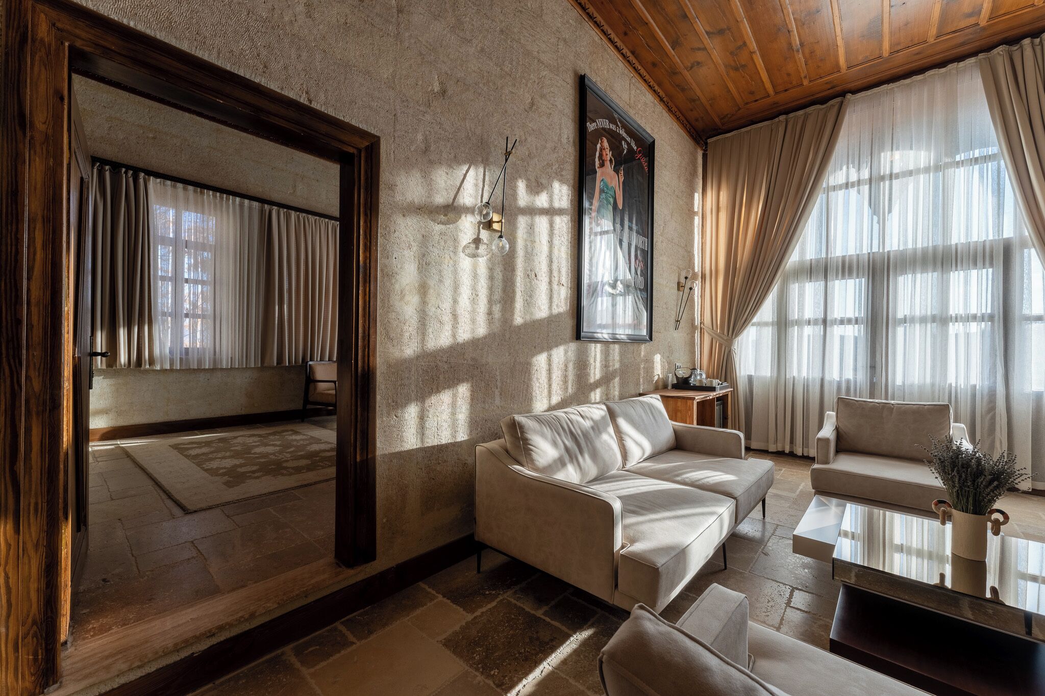A living room with a sofa, armchairs, a coffee table, and a large window with curtains.