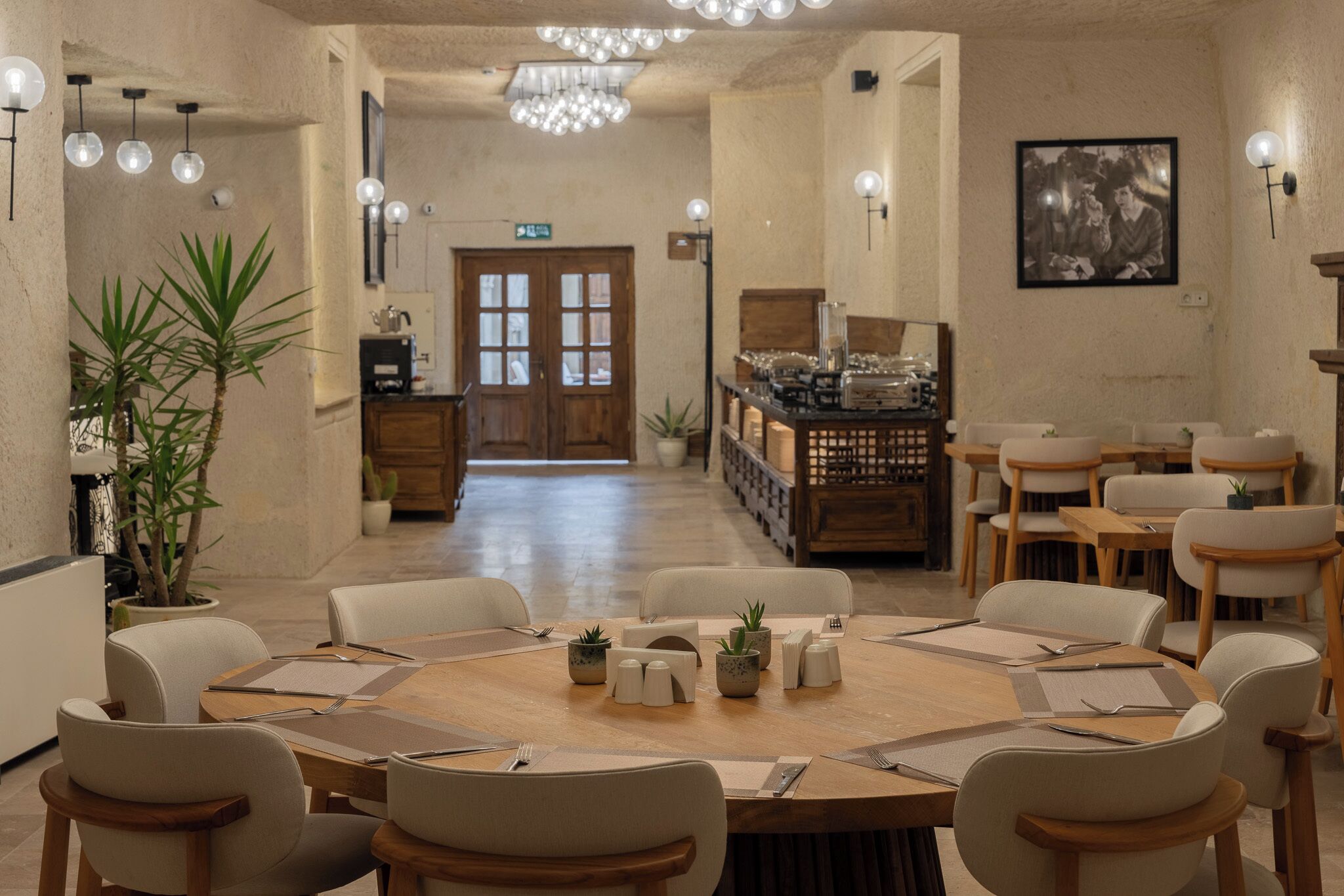 A dining area with round tables, chairs, and potted plants.