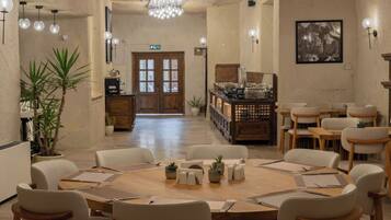 A dining area with round tables, chairs, and potted plants.