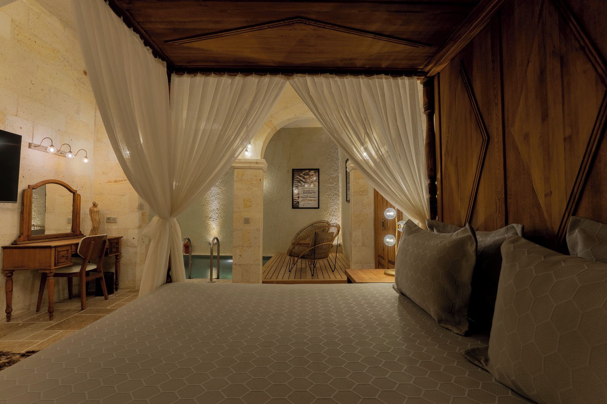 A bedroom with a large bed, a wooden desk with a mirror, and a chair.