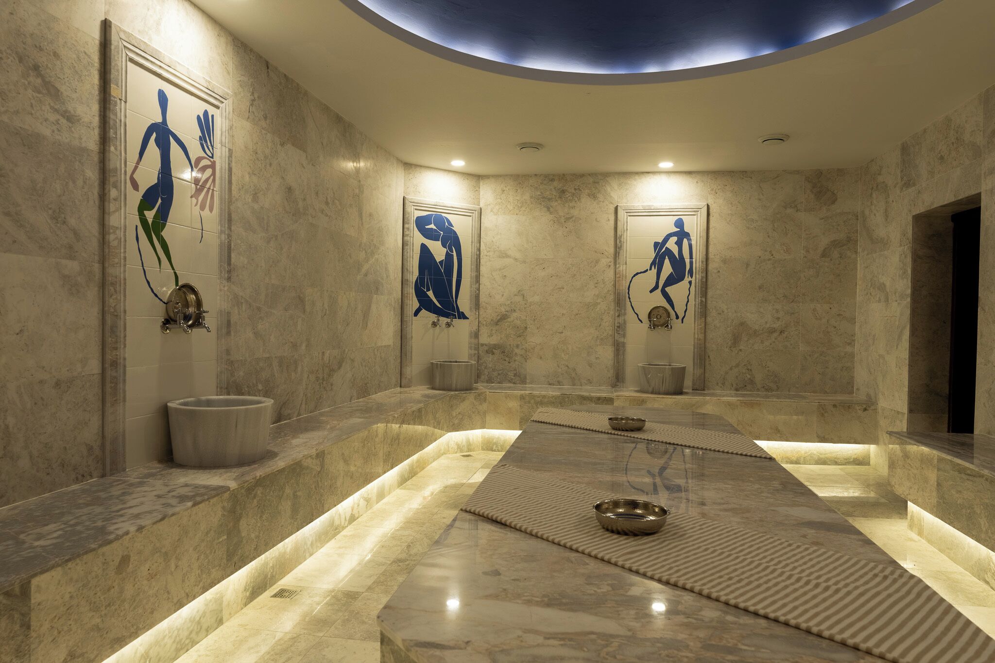 A modern bathroom with marble walls, a central heated floor, and abstract wall art.