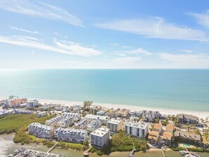 Un quartier résidentiel situé sur la côte, comprenant plusieurs immeubles d’appartements, une plage et un port de plaisance.