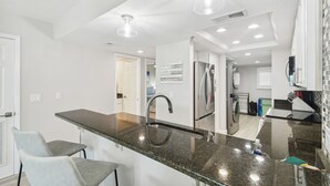 Eine moderne Küche mit Granit Arbeitsplatten, Edelstahlgeräten und Pendelleuchten.