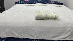 A bed with a floral-patterned bedspread and pillows, a striped pillow, and a dark wooden headboard. - The Last Resort with private entrance. In Basement. (Winnipeg)