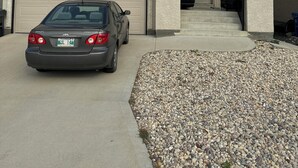 A two-story house with a garage, a driveway, and a gravel area in front. - The Last Resort with private entrance. In Basement. (Winnipeg)