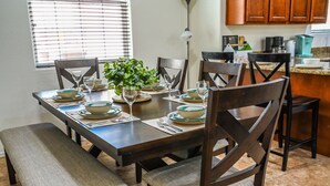 Una mesa de comedor dispuesta con platos, vasos y una planta.