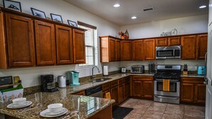 Una cocina con armarios de madera, encimeras de granito, un microondas de acero inoxidable y una estufa a gas.