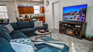 Una sala de estar con un sofá modular, un televisor de pantalla plana y una chimenea.